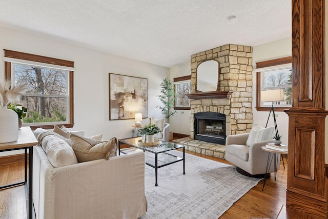 living room with a textured ceiling, a fireplace, and wood finished floors