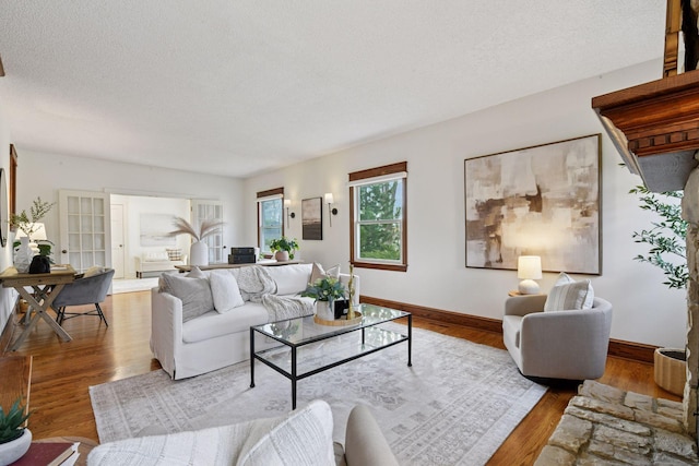 living room with a textured ceiling, baseboards, and wood finished floors