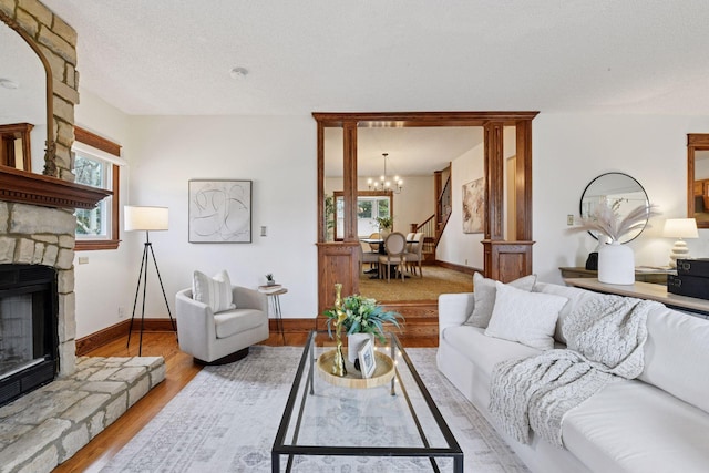 living room featuring stairway, baseboards, a chandelier, a fireplace, and wood finished floors
