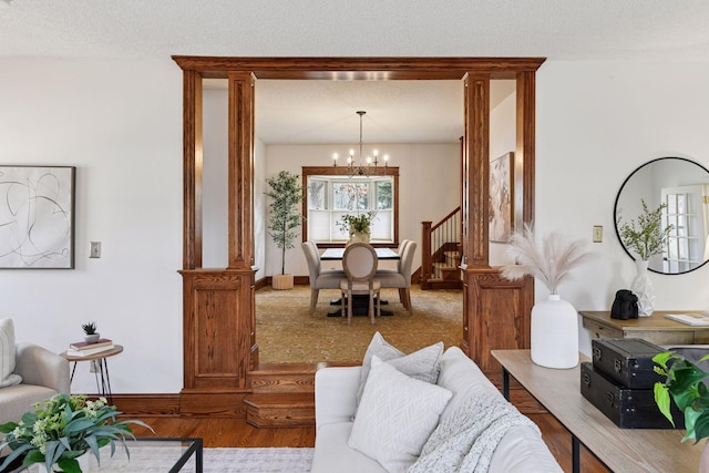 living area featuring baseboards, a textured ceiling, wood finished floors, and an inviting chandelier