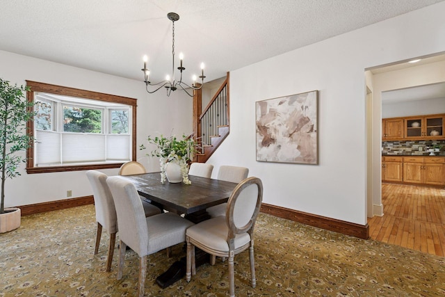 dining space featuring baseboards, a notable chandelier, stairs, and a textured ceiling