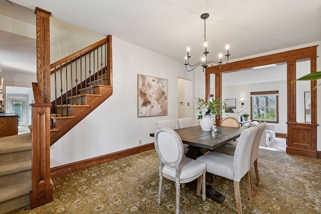 dining space featuring baseboards, a textured ceiling, a chandelier, and stairway