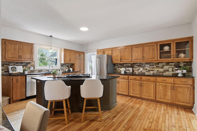 kitchen featuring light wood-style flooring, a breakfast bar, brown cabinets, a kitchen island, and appliances with stainless steel finishes