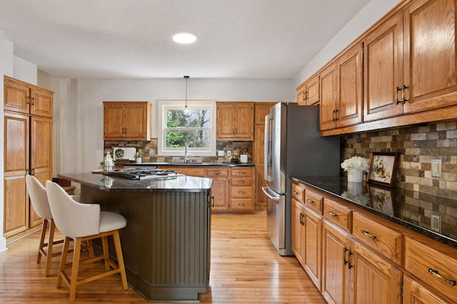 kitchen featuring brown cabinets, light wood-type flooring, a kitchen breakfast bar, and a sink
