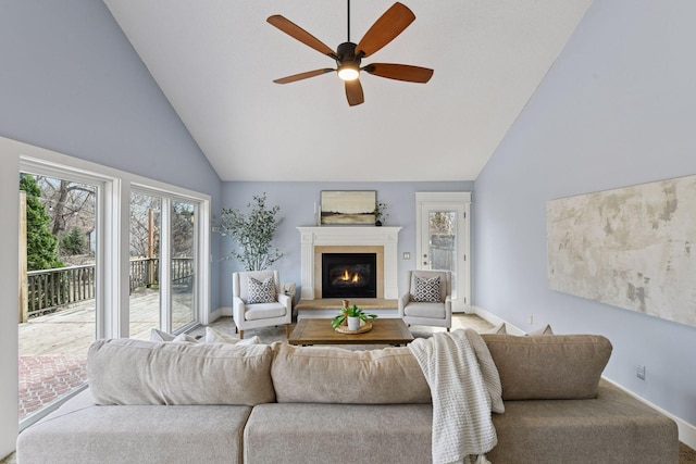 living room with high vaulted ceiling, a glass covered fireplace, baseboards, and ceiling fan