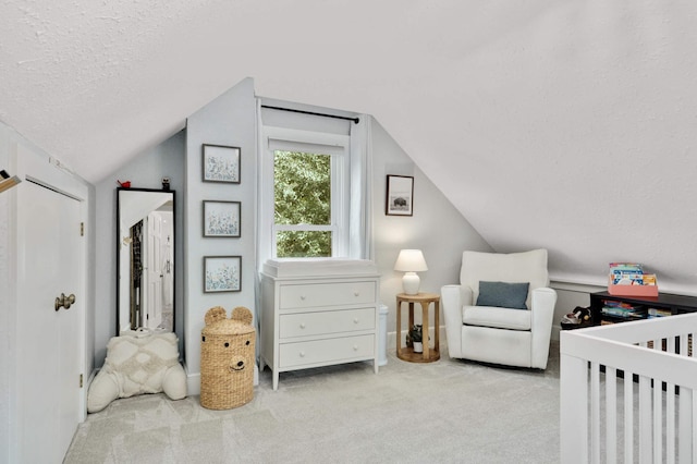 bedroom with carpet floors, a nursery area, vaulted ceiling, and a textured ceiling