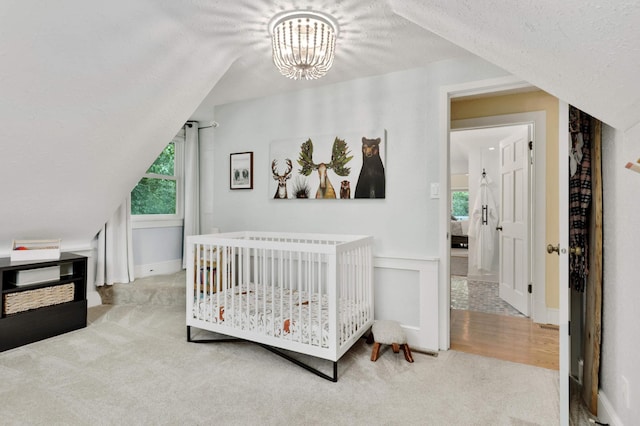 bedroom with an inviting chandelier, carpet floors, lofted ceiling, and a textured ceiling