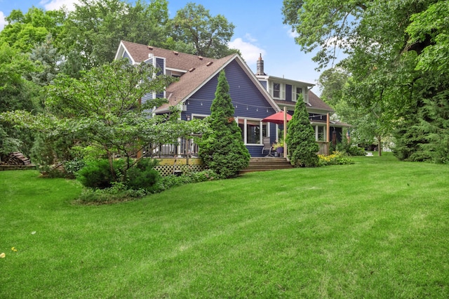 exterior space featuring a chimney, a shingled roof, and a lawn