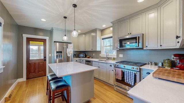 kitchen featuring light wood-type flooring, stainless steel appliances, a kitchen island, and sink