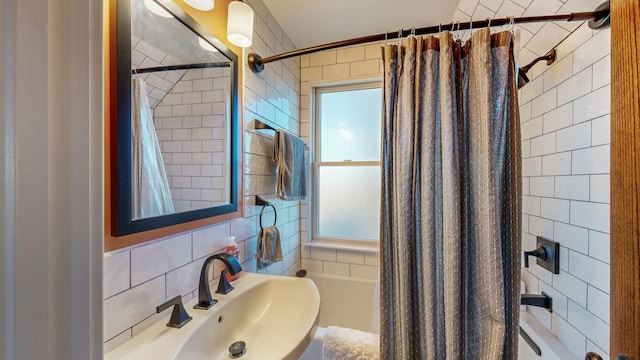 bathroom featuring tile walls, shower / bath combo with shower curtain, and sink