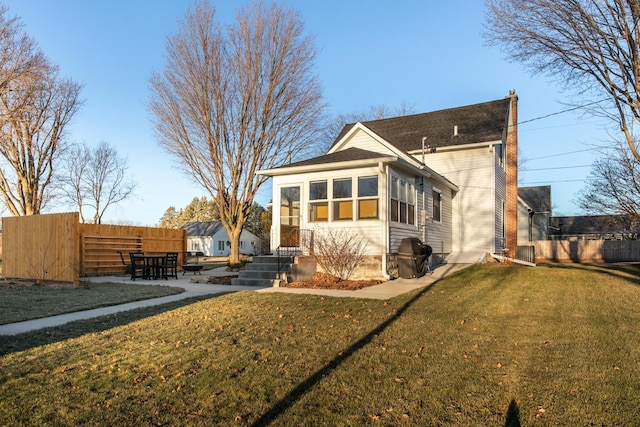 rear view of house featuring a yard and a sunroom