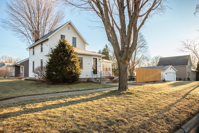 view of front facade with an outbuilding, a front lawn, and a garage