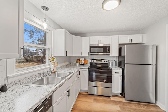 kitchen featuring stainless steel appliances, white cabinetry, and hanging light fixtures