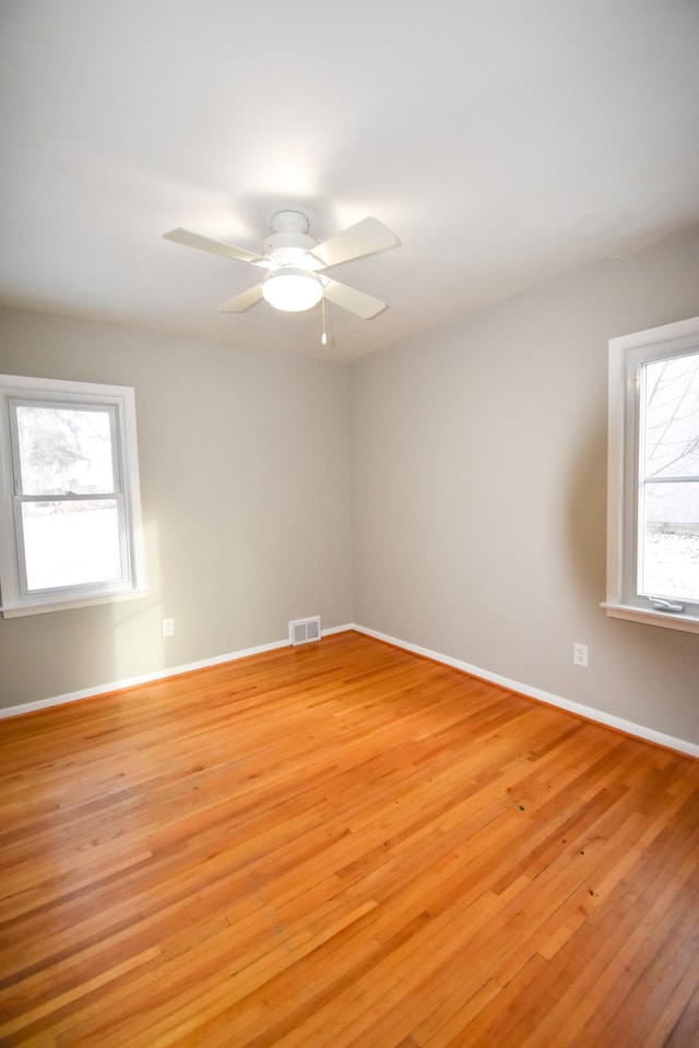 unfurnished room featuring plenty of natural light, ceiling fan, and light wood-type flooring