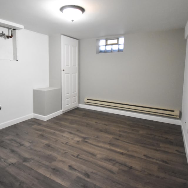 basement with dark hardwood / wood-style floors and a baseboard radiator