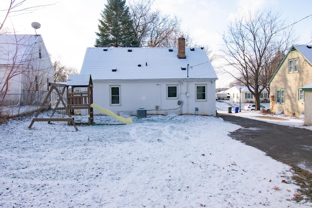 snow covered house with a playground and central AC unit