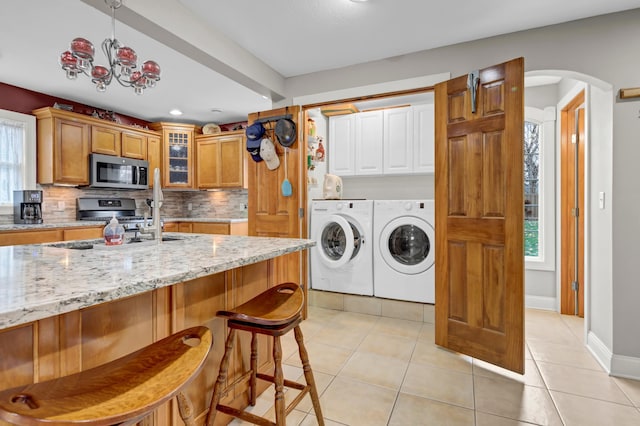 laundry room with separate washer and dryer, cabinets, light tile patterned flooring, and a healthy amount of sunlight