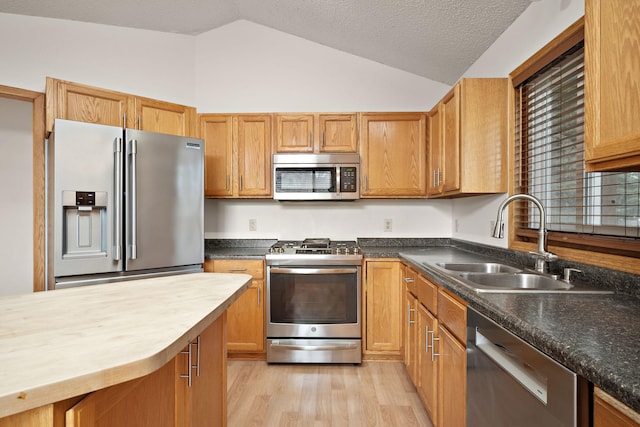 kitchen with appliances with stainless steel finishes, a textured ceiling, sink, light hardwood / wood-style floors, and lofted ceiling