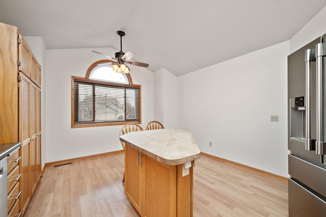 kitchen with lofted ceiling, ceiling fan, a kitchen island, high quality fridge, and light hardwood / wood-style floors