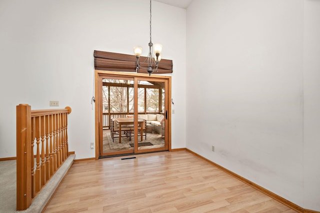 unfurnished room with a chandelier and light wood-type flooring