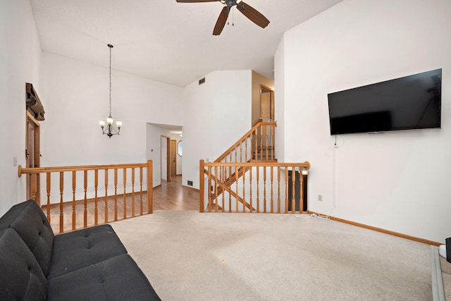 living room featuring a high ceiling, ceiling fan with notable chandelier, and hardwood / wood-style flooring