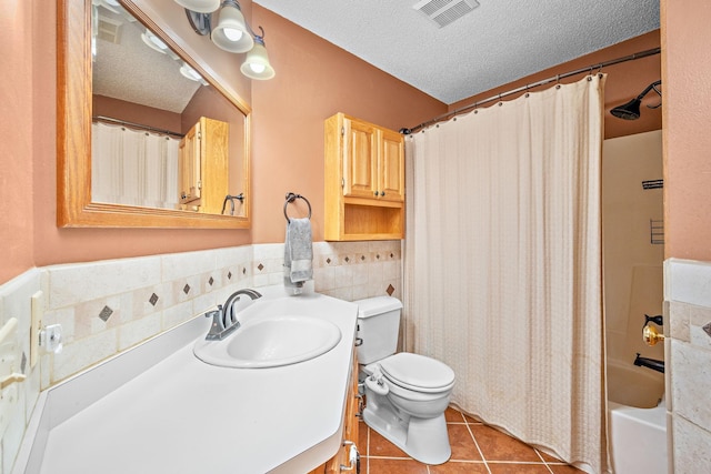 full bathroom featuring tile patterned flooring, toilet, a textured ceiling, and shower / tub combo with curtain