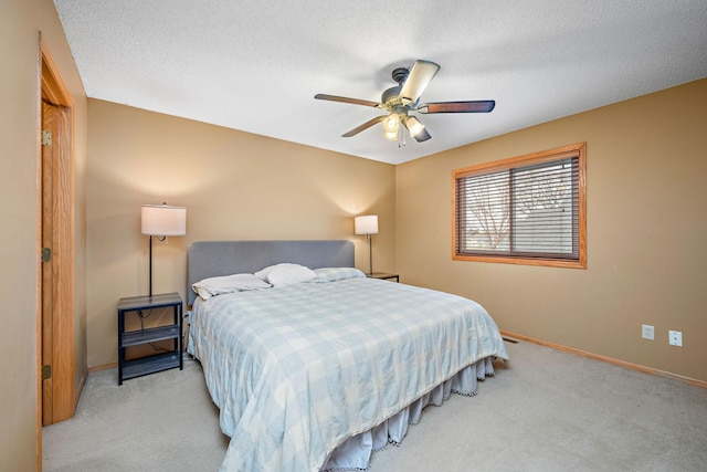 bedroom featuring a textured ceiling, light colored carpet, and ceiling fan