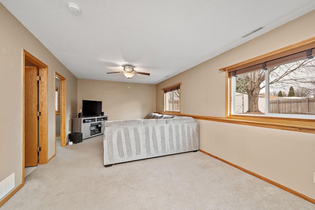 living room featuring ceiling fan, light colored carpet, and a textured ceiling