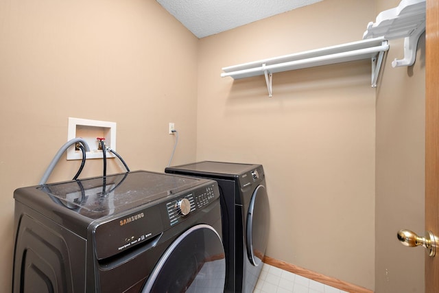 laundry room featuring washing machine and clothes dryer and a textured ceiling