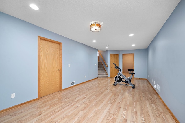 exercise area with a textured ceiling and light wood-type flooring