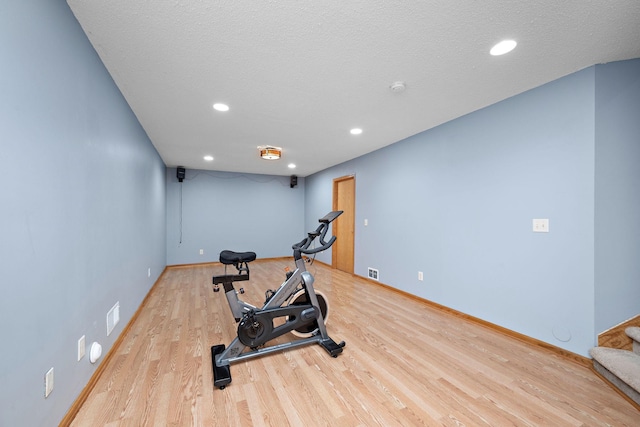 exercise area featuring a textured ceiling and light wood-type flooring