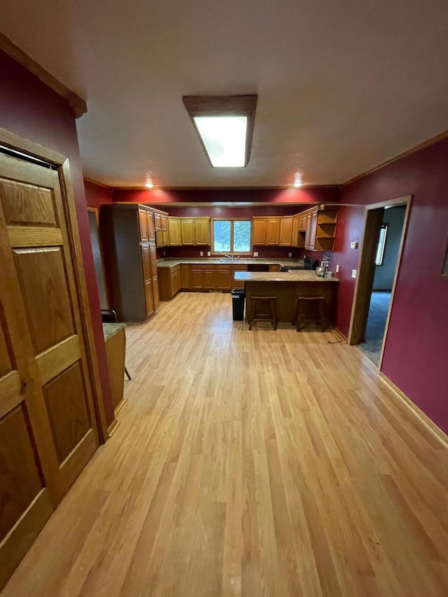 kitchen featuring a kitchen bar, light hardwood / wood-style flooring, a center island, and sink