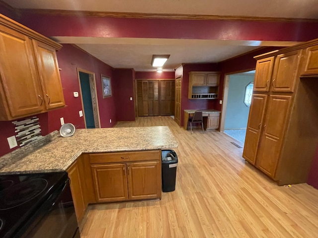 kitchen featuring light stone countertops, light wood-type flooring, and kitchen peninsula