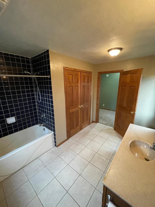 bathroom with tile patterned floors, vanity, a textured ceiling, and tiled shower / bath