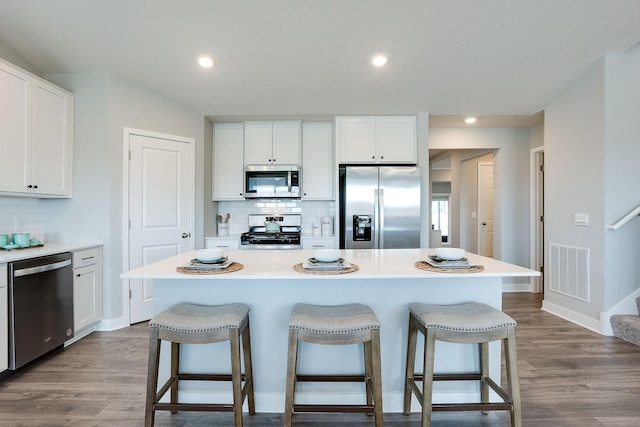 kitchen with a kitchen breakfast bar, a center island, white cabinetry, and appliances with stainless steel finishes