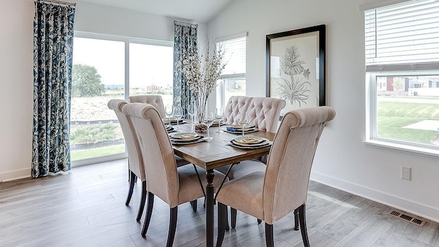 dining room with plenty of natural light, light hardwood / wood-style floors, and vaulted ceiling