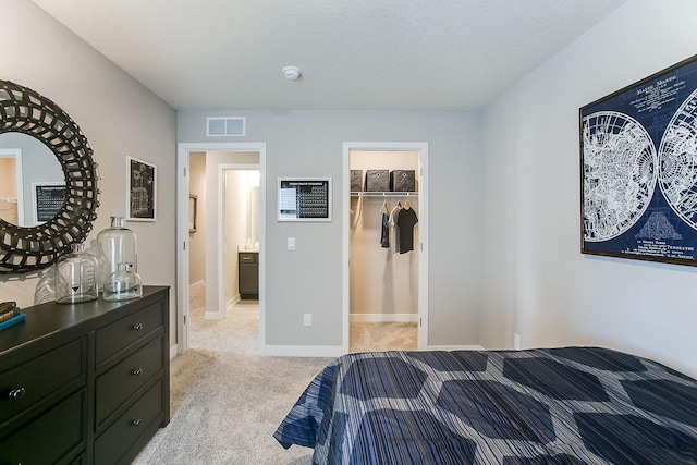 bedroom featuring light colored carpet, a spacious closet, a textured ceiling, and a closet