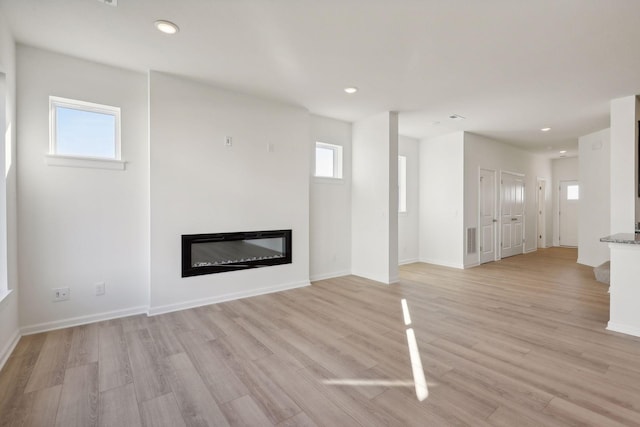 unfurnished living room featuring a healthy amount of sunlight and light wood-type flooring