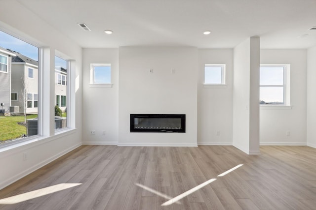 unfurnished living room featuring plenty of natural light and light hardwood / wood-style floors