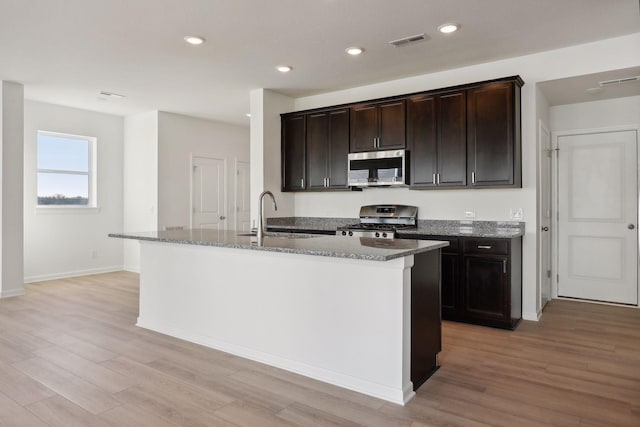 kitchen featuring sink, an island with sink, light hardwood / wood-style flooring, and appliances with stainless steel finishes