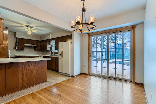 kitchen with kitchen peninsula, decorative light fixtures, white fridge with ice dispenser, ceiling fan with notable chandelier, and sink