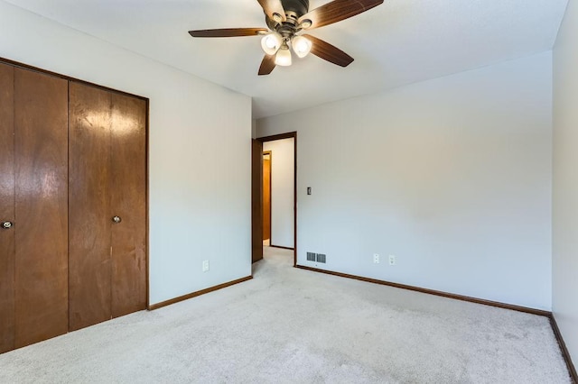 unfurnished bedroom featuring ceiling fan, light colored carpet, and a closet