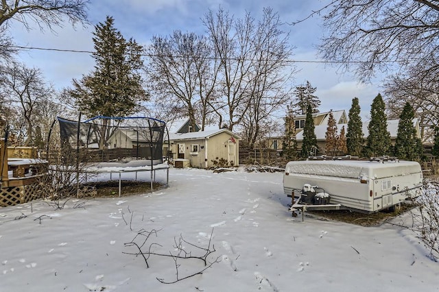 snowy yard featuring a storage shed and a trampoline