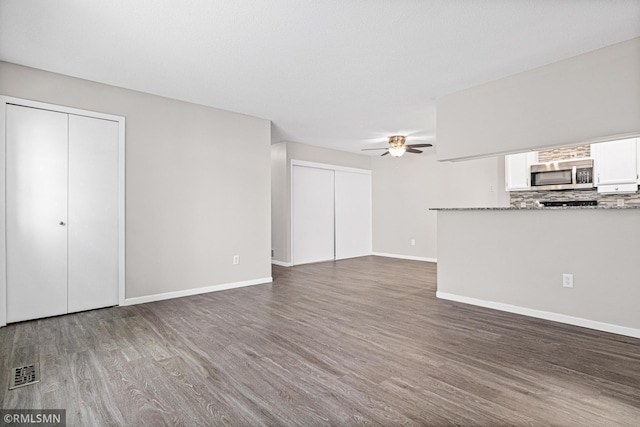 unfurnished living room featuring ceiling fan and dark hardwood / wood-style flooring