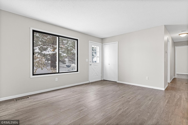 unfurnished room featuring hardwood / wood-style flooring and a textured ceiling