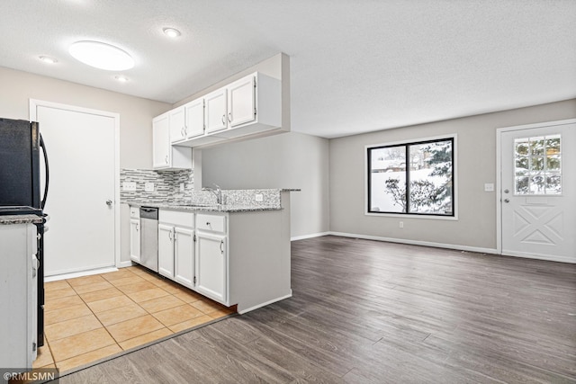 kitchen with white cabinetry, stainless steel dishwasher, a textured ceiling, and light wood-type flooring