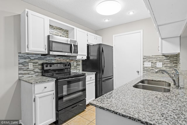 kitchen featuring white cabinetry, sink, backsplash, light tile patterned floors, and black appliances