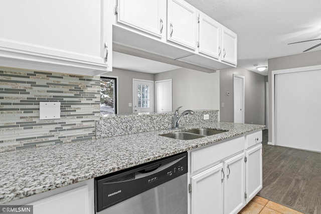 kitchen featuring light stone countertops, dishwasher, sink, wood-type flooring, and white cabinets