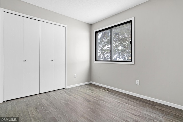 unfurnished bedroom with wood-type flooring, a textured ceiling, and a closet