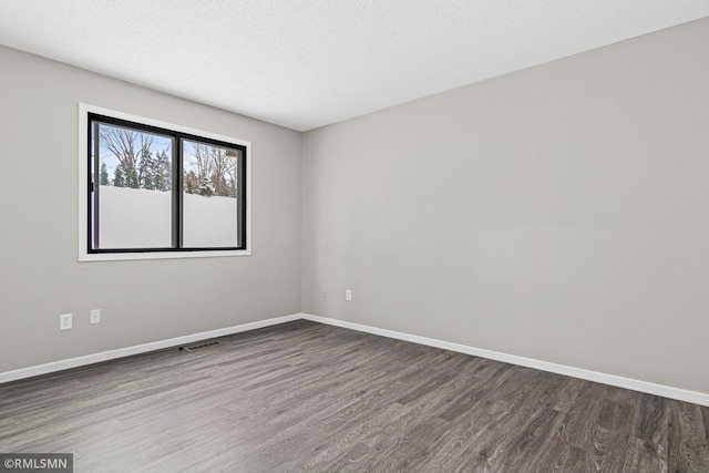 spare room featuring dark wood-type flooring and a textured ceiling